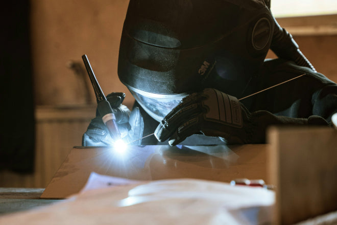 Welder performing TIG welding with focus on precision and clean weld quality in a professional workshop setting.